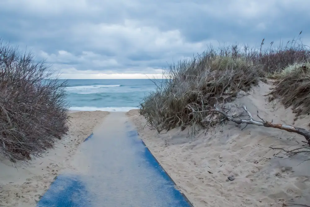 View of walkway leading to Coast Guard Beach in Cape Cod on a cloudy day with seagrasses on the dunes to show one of the best beaches in the United States
