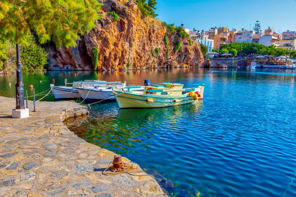 Fishing boats pictured for a piece on the best areas to stay in Crete, Greece, with small boats floating on a lake in Agios Nikolaos
