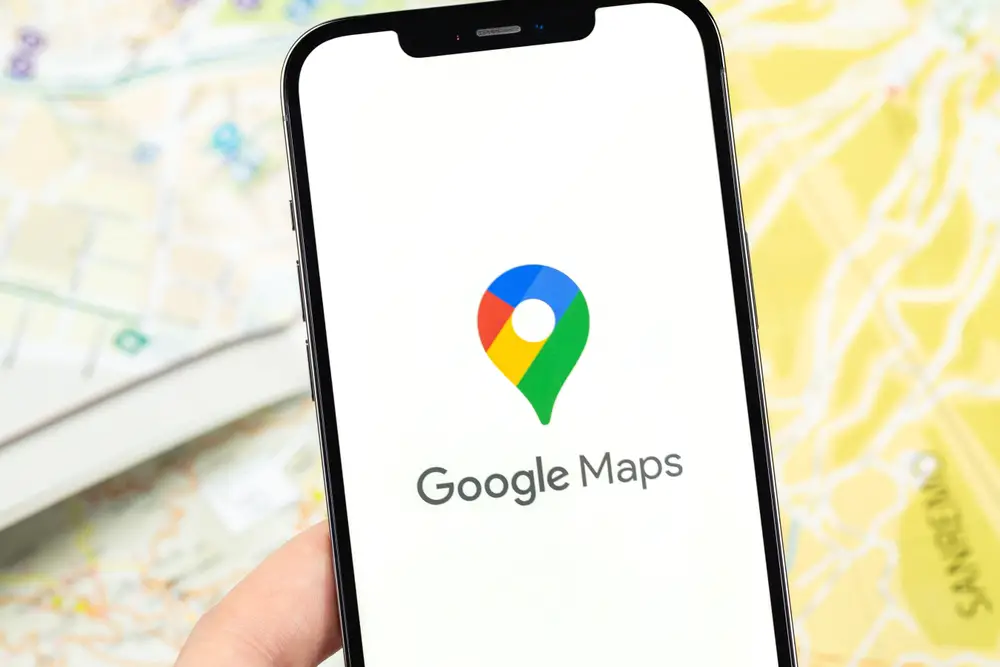 Google Maps app loaded on a smartphone over a blurred map shows how you can use this trip planning app to navigate and plan a route