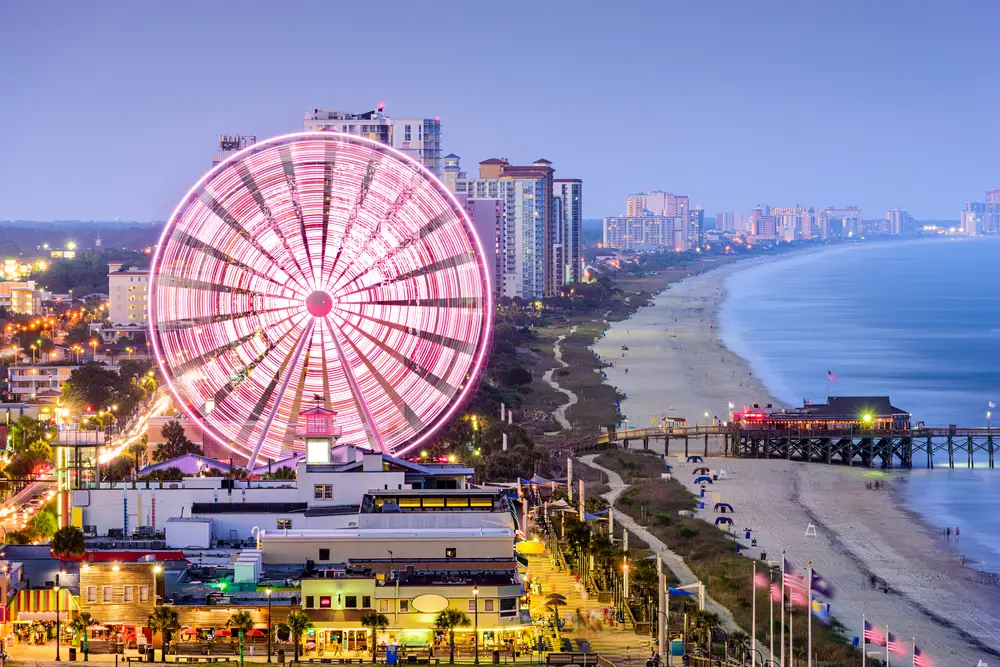 For a roundup of the best places to visit in South Carolina, a giant amusement park and the large boardwalk and several hotels along the beach pictured in the evening
