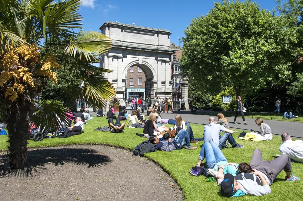 St. Stephen's Green, pictured on a clear summer day with people relaxing in the park, pictured for a roundup of the best areas to stay in Dublin