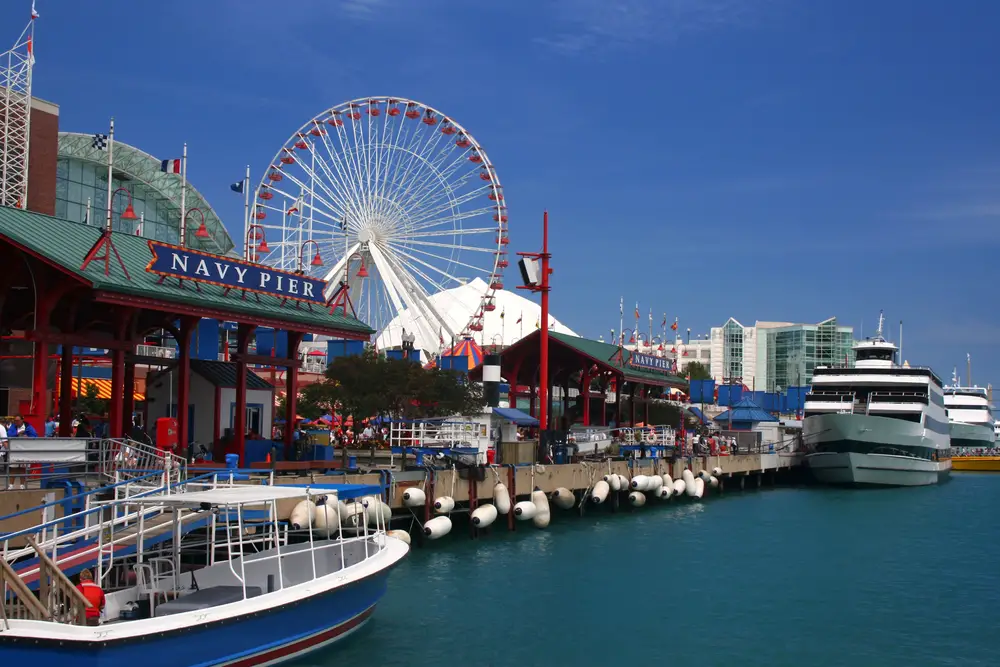 Boats and a Ferris wheel pictured on the Navy Pier, one of our favorite things to do in Chicago, with a blue sky in the background
