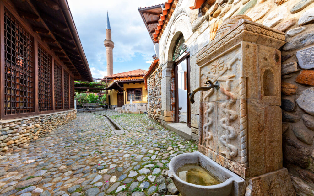 Old fountain with the minaret of Halveti's Tekke Mosque pictured in Prizren pictured for a piece titled Is Kosovo Safe to Visit