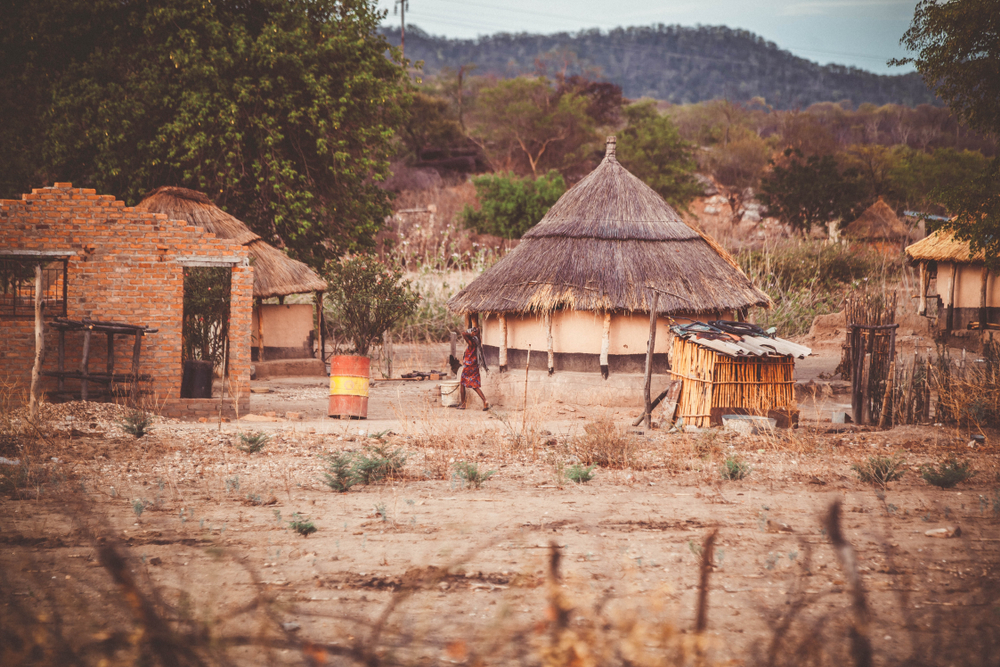 Traditional house in Zimbabwe pictured with its mud hut and thatched roof sitting on the dirt desert