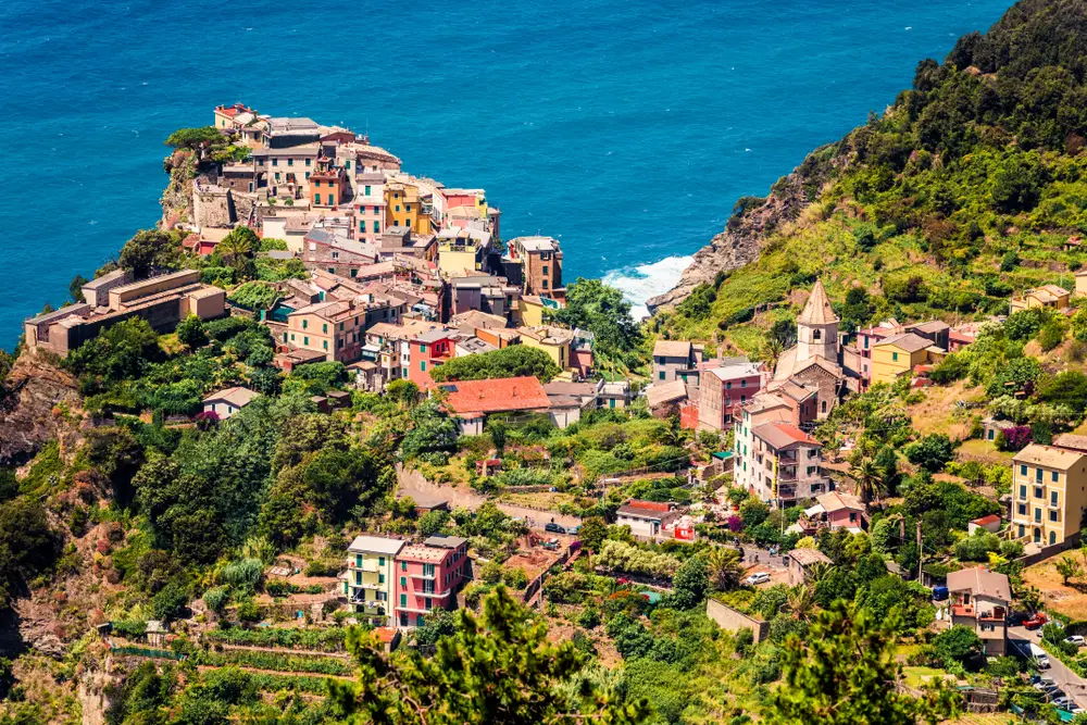 The village of Corniglia off the coast shown on a beautiful spring day with terraced olive groves during the best time to visit Cinque Terre in spring and early summer