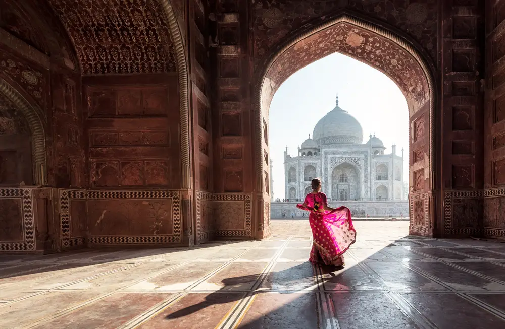 To show that India can be safe to visit, a woman in a red saree stands under an archway at the Taj Mahal campus