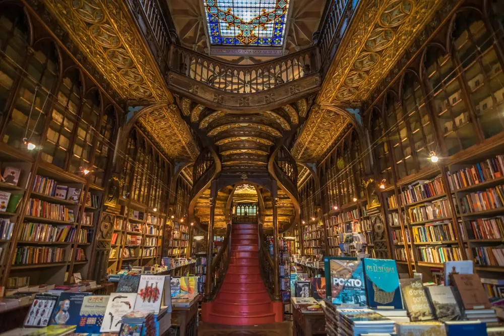 One of the world's most beautiful bookstores, Lello Bookstore, seen from the inside with stained glass and intricate woodwork. Shown as example of things to do during the best time to visit Porto