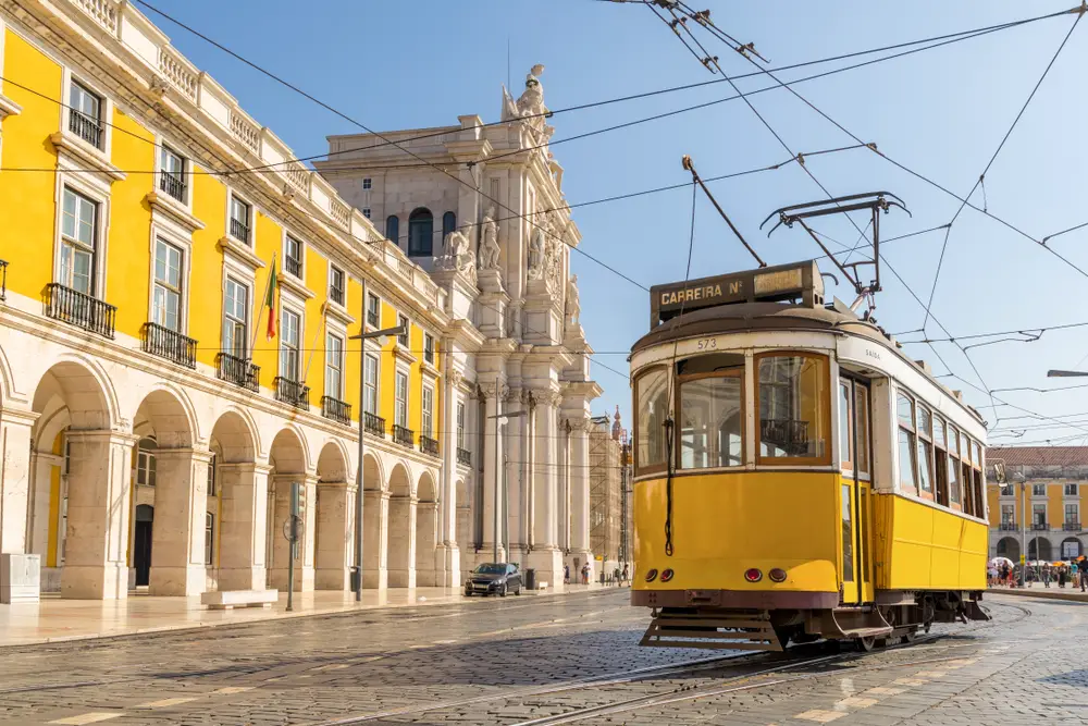 Yellow tram and yellow building in the Praca do Comercio in Baixa, one of the best places to stay in Lisbon, Portugal