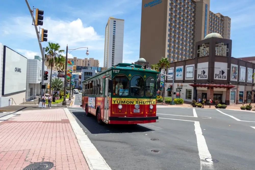 Red trolley running along the street in the shopping district of Tuom for a guide to whether or not Guam is safe to visit