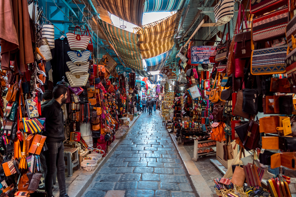 Πολύχρωμη αγορά παζαριών με εμπορεύματα να κρέμονται κατά μήκος ενός στενού κατά τη συνολική καλύτερη στιγμή για να επισκεφθείτε την Τυνησία