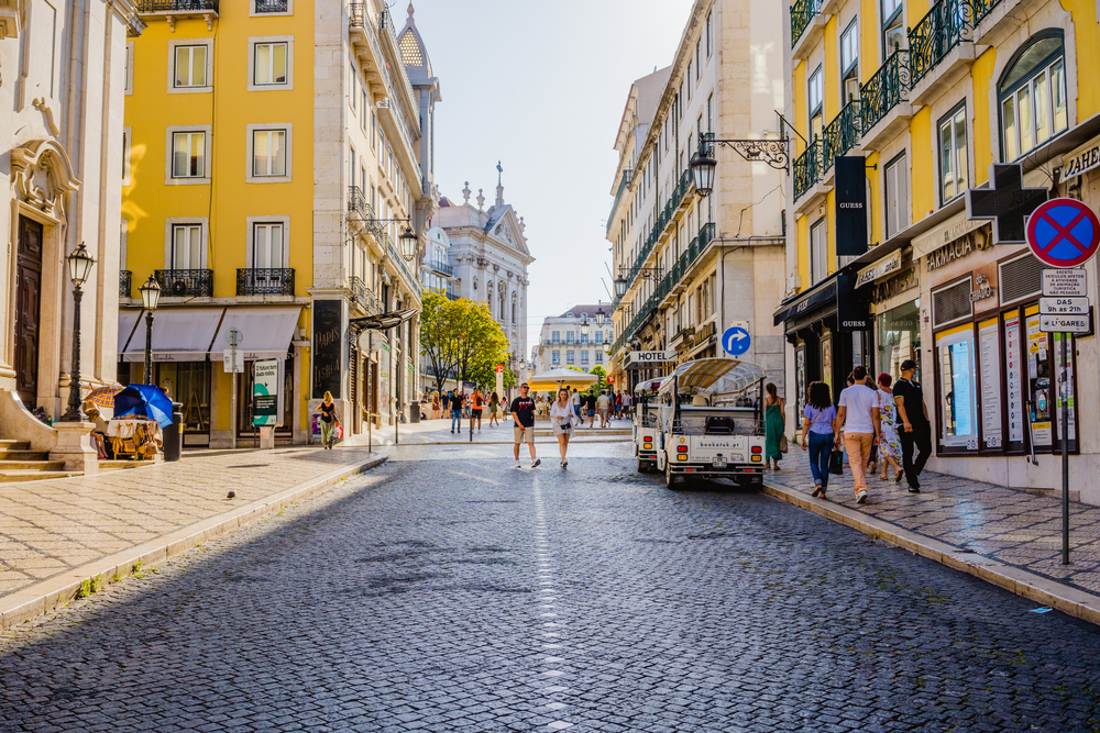 Άνθρωποι που περπατούν κατά μήκος του λιθόστρωτου δρόμου Chiado στη Λισαβόνα, μια από τις καλύτερες περιοχές για να μείνετε όταν επισκέπτεστε