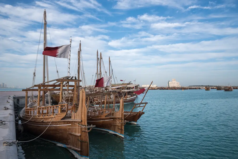 Traditional dhow boats in the water off the coast of Doha for a frequently asked questions section on the best time to visit Qatar