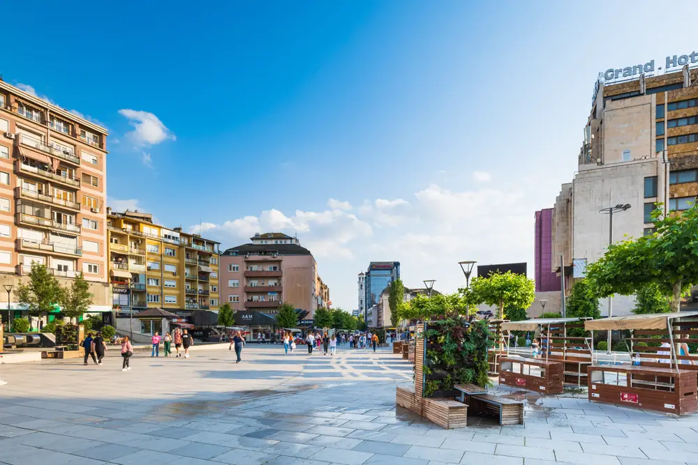 Stone street in the downtown area of Kosovo pictured between big buildings with blue skies overhead