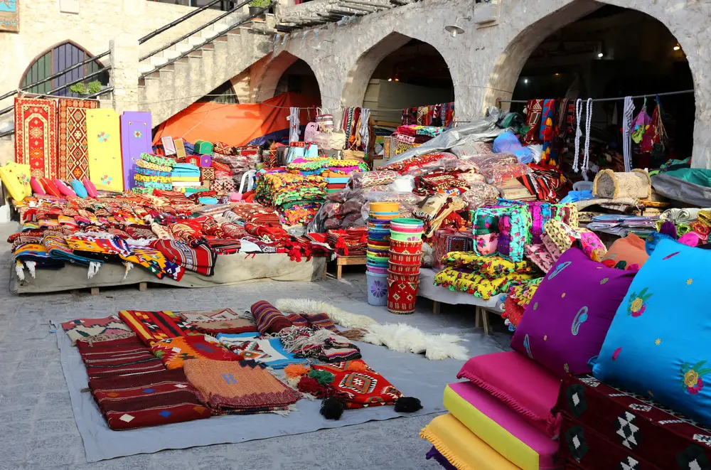 Colorful cloth and products for sale at Souq Waqif market during the cheapest time to visit Qatar