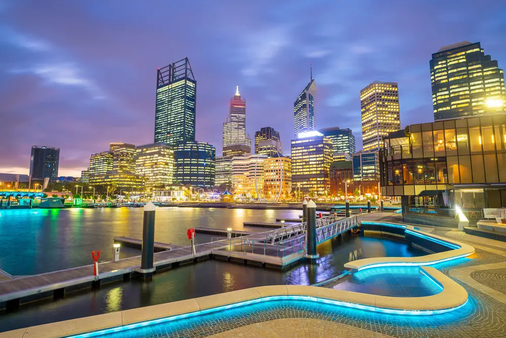 Downtown skyline of Perth with its modern buildings and illuminated concrete walkway next to the ocean
