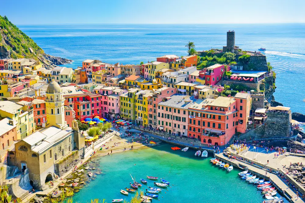 Aerial view of Vernazza and boats lining the shore with colorful buildings during the worst time to visit Cinque Terre in late summer and fall