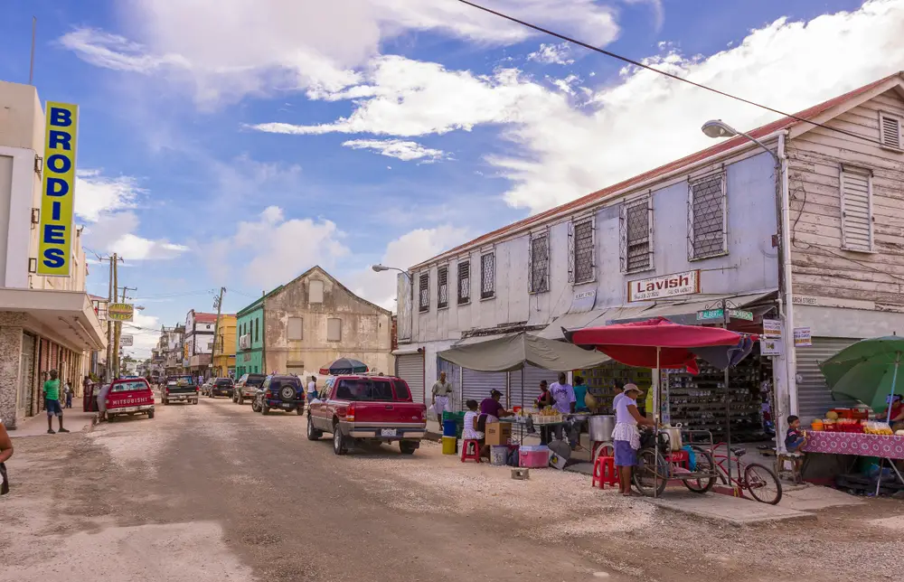 Photo of the busy market in Belize City pictured with people mulling about under a blue sky for a piece titled Is Belize Safe to Visit