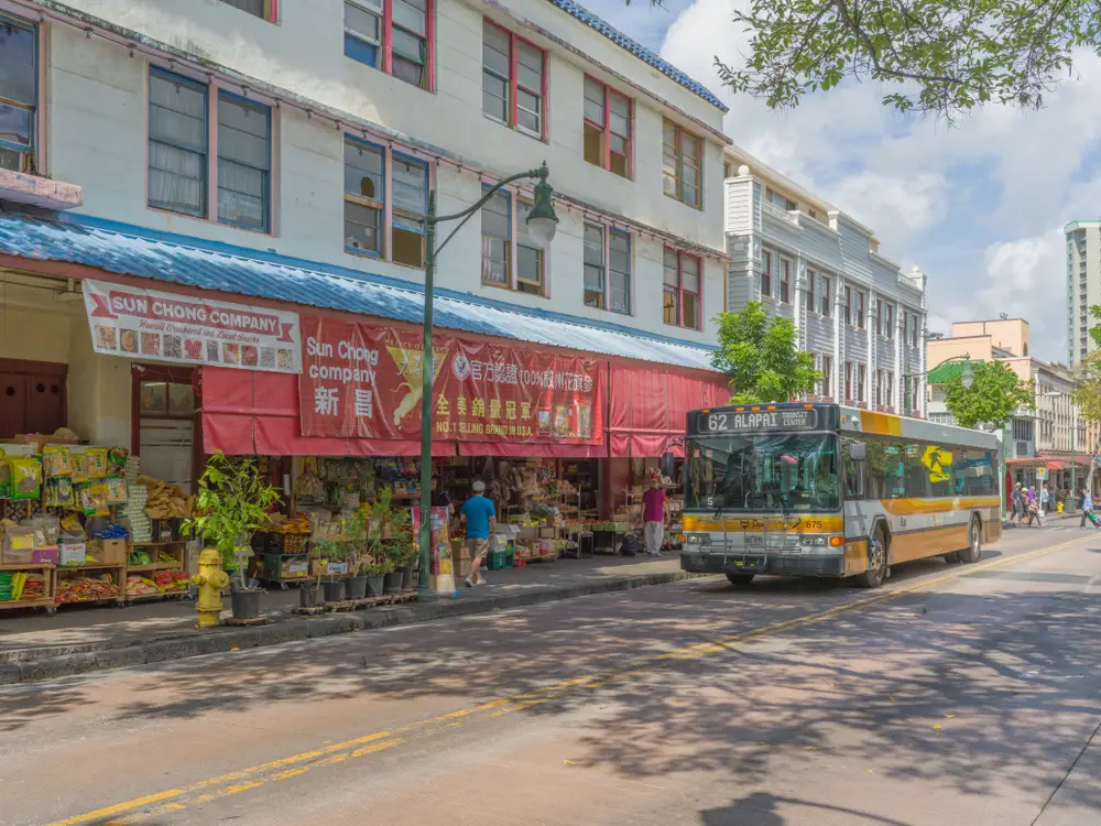 To illustrate the safest and least safe areas to visit on Oahu, a photo of the Chinatown area is shown, with its bustling people and vehicles making their way down the road