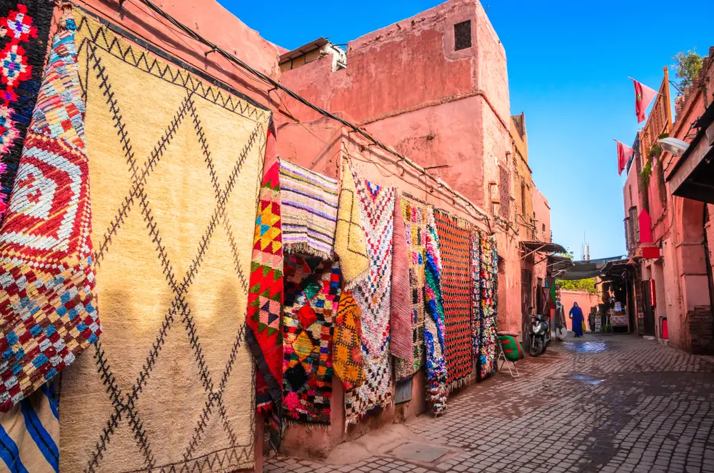 Tapestries hanging on the walls and doors of shops in the Old Medina area of town for a piece titled Is Marrakech Safe to Visit