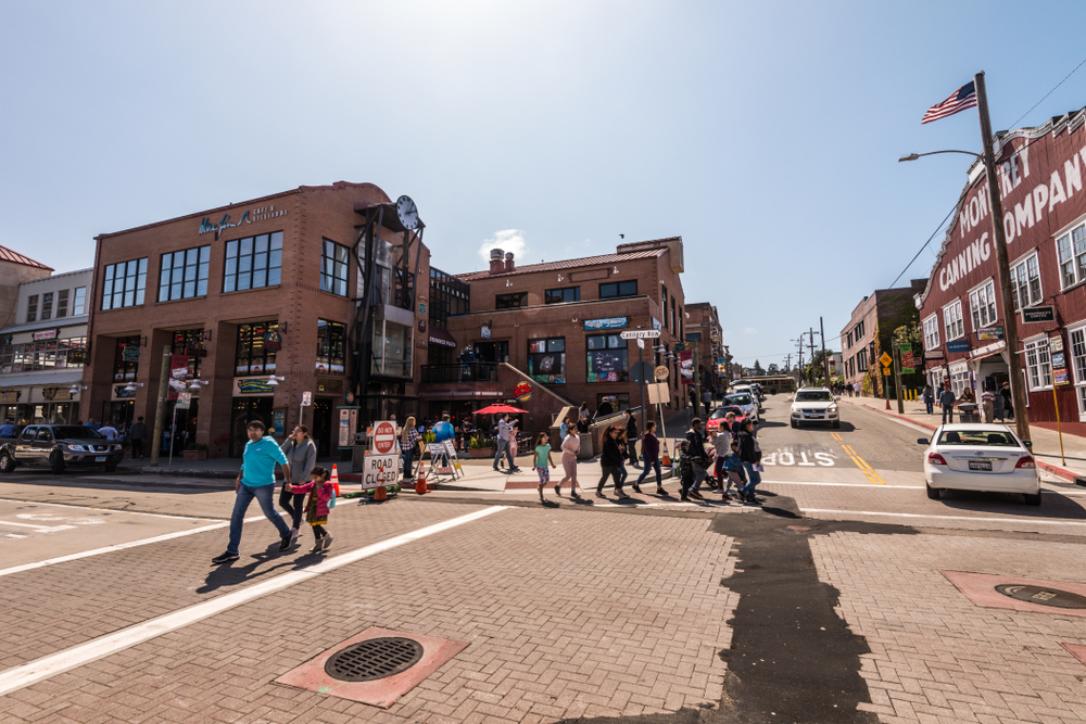 Cannery Row, one of the best areas to stay in Monterey California, pictured with people walking all around the town
