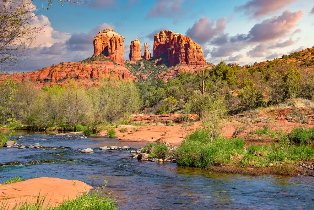 Cathedral Rock seen from afar on a nice day with clouds overhead as a creek runs through the foreground for a piece showing the best boutique hotels in Sedona
