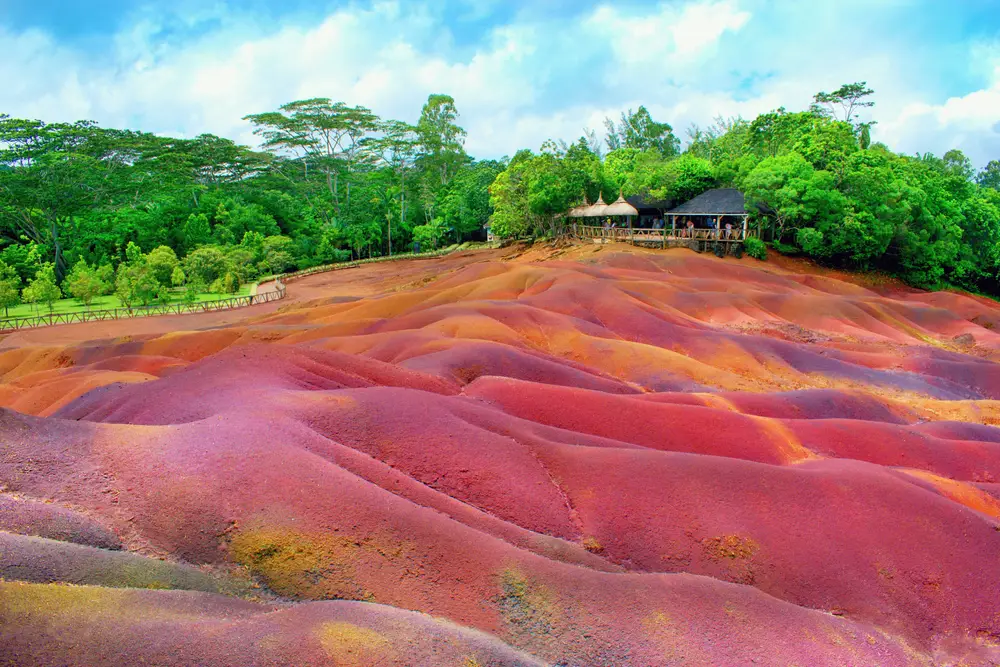 Picturesque pink and purple sand on the hillside in the Black River Gorges National Park to answer whether Mauritius is safe to vacation to, with green trees around it