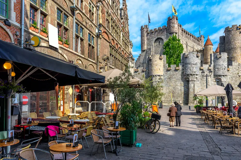View from a table of a cafe in Gent with a castle straight ahead pictured for a piece on whether or not it's safe to visit Belgium