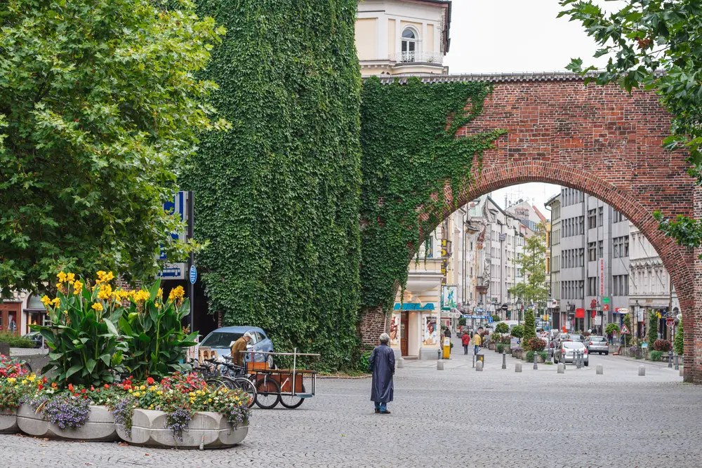 Couple people standing below the green vine-covered brick arch in Sendling, a top pick when considering where to stay in Munich