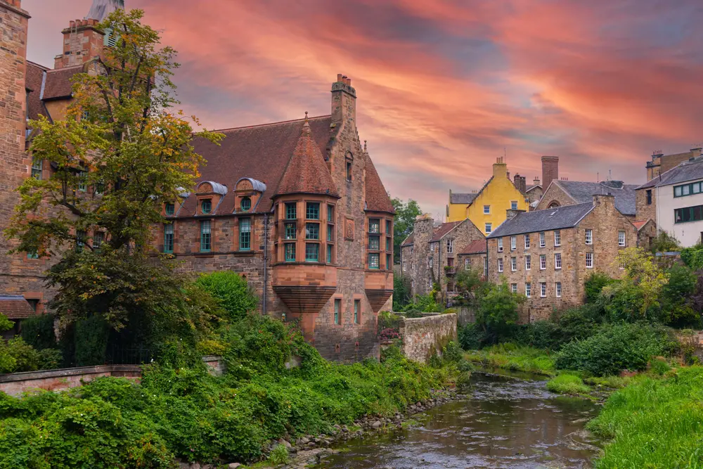 Dean's Village in Edinburgh at sunset with greenery and a creek running through for a piece on the best castle hotels in Scotland