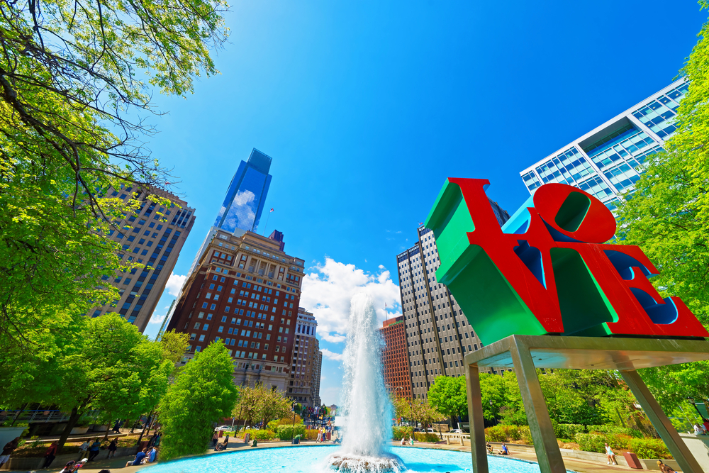 Love Park sculpture with fountain and downtown buildings behind it shows Philadelphia as one of the 10 cheap places to fly to