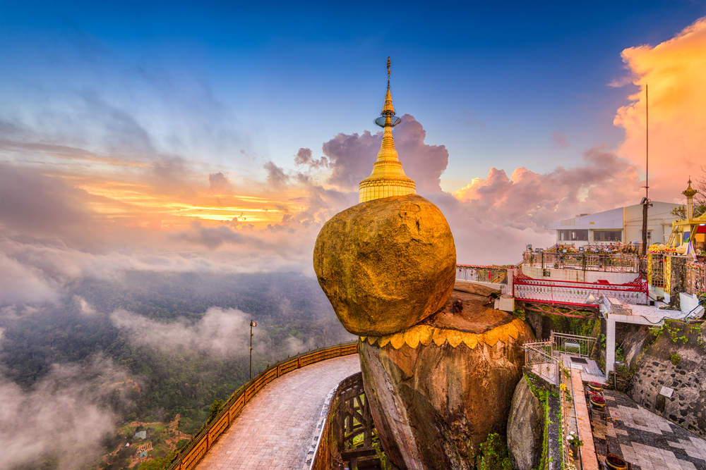 Golden Rock Myanmar pictured above a cloudy sky with a walkway high above the valley below
