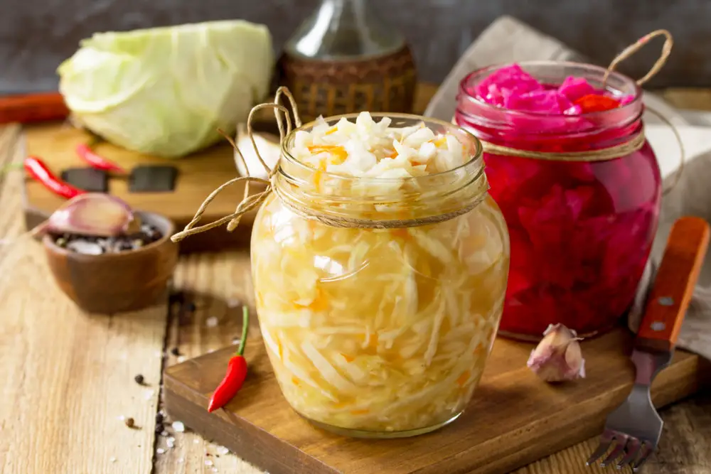 Sauerkraut, among the best German food items to try, and pickled beets in jars on a table with ingredients behind them