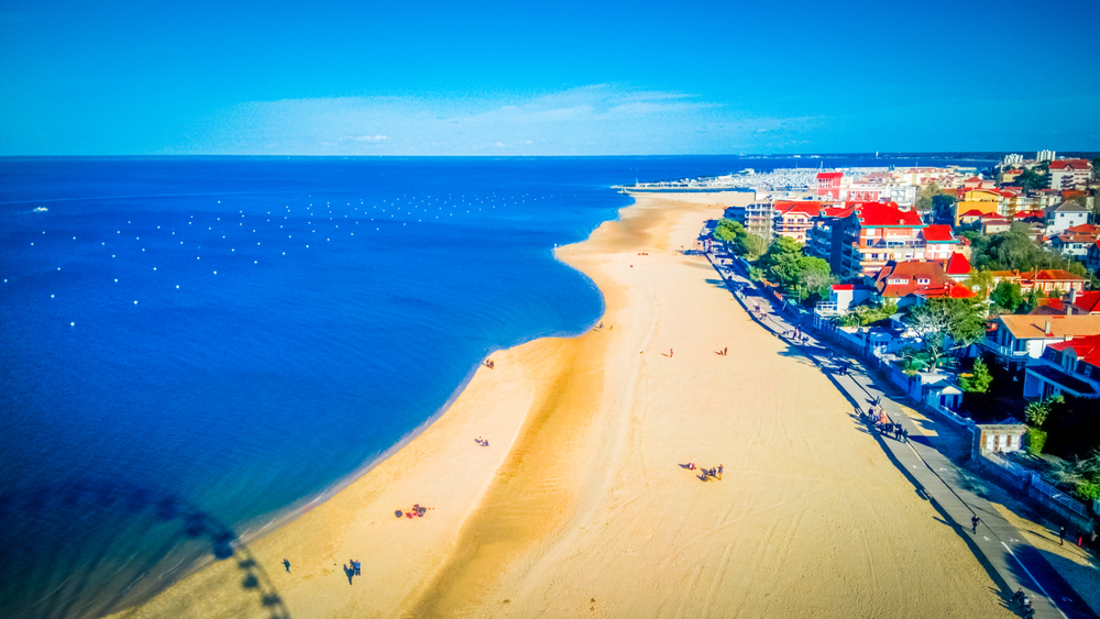 Aerial view of the beach with the shadow of a Ferris wheel in Arcachon, France as one of the top family vacation destinations 