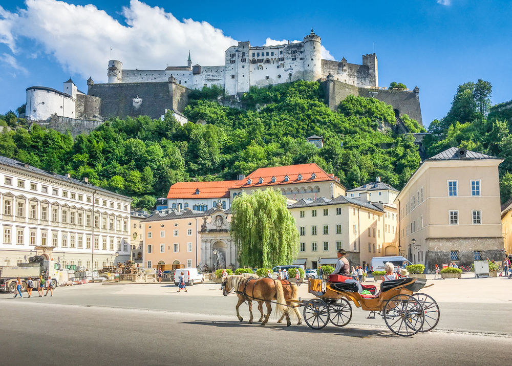 Gorgeous view of a horse-drawn carriage in front of a castle in Salzburg, a top pick for the best areas to stay in Austria