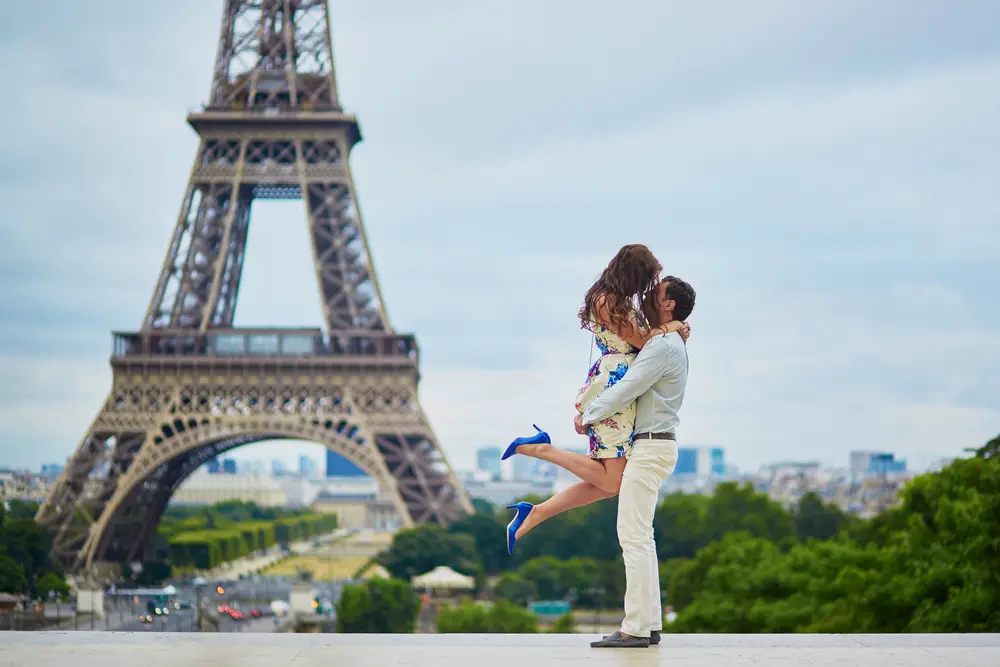 Newly married woman jumps into her husband's arms in front of the Eiffel Tower in Paris, France, one of the top honeymoon destinations globally