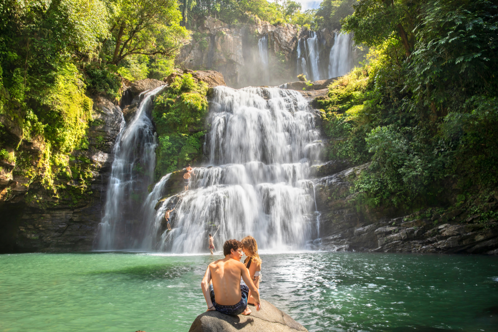 View of a couple embracing in front of a waterfall in Manuel Antonio National Park in Costa Rica indicates why this is one of the best honeymoon destinations