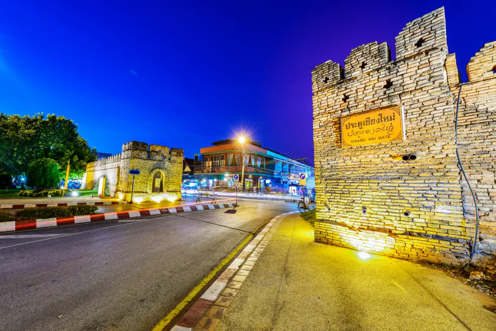 West gate of the old city in Chiang Mai pictured at night with the stone walls illuminated