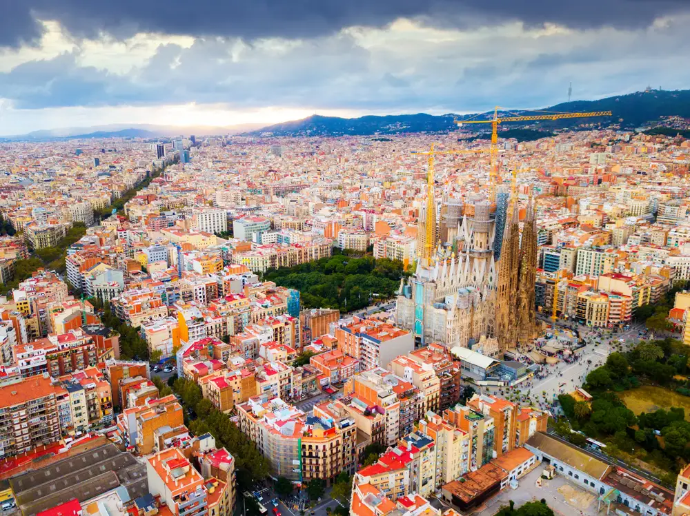 Aerial view of Barcelona with Sagrada Familia and colorful buildings seen with clouds overhead for a list of the best places for tourists in the world