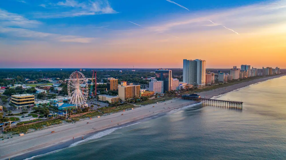Myrtle Beach boardwalk and pier seen from an aerial view at sunset with nearly empty beaches for a list of the best East Coast vacations spots