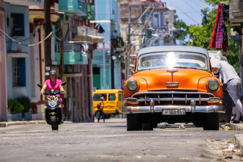 People in colorful cars and on motorcycles pictured making their way through the streets of Havana