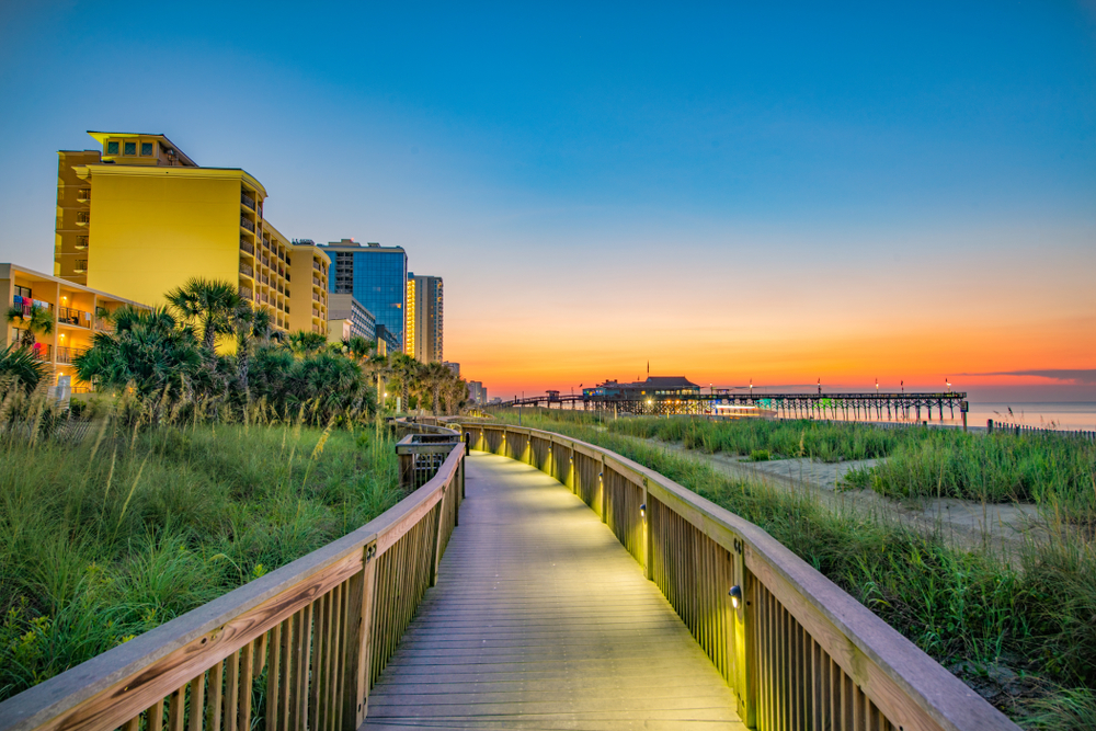 Neat night view of the boardwalk in Myrtle Beach pictured with a golden sunset in the background