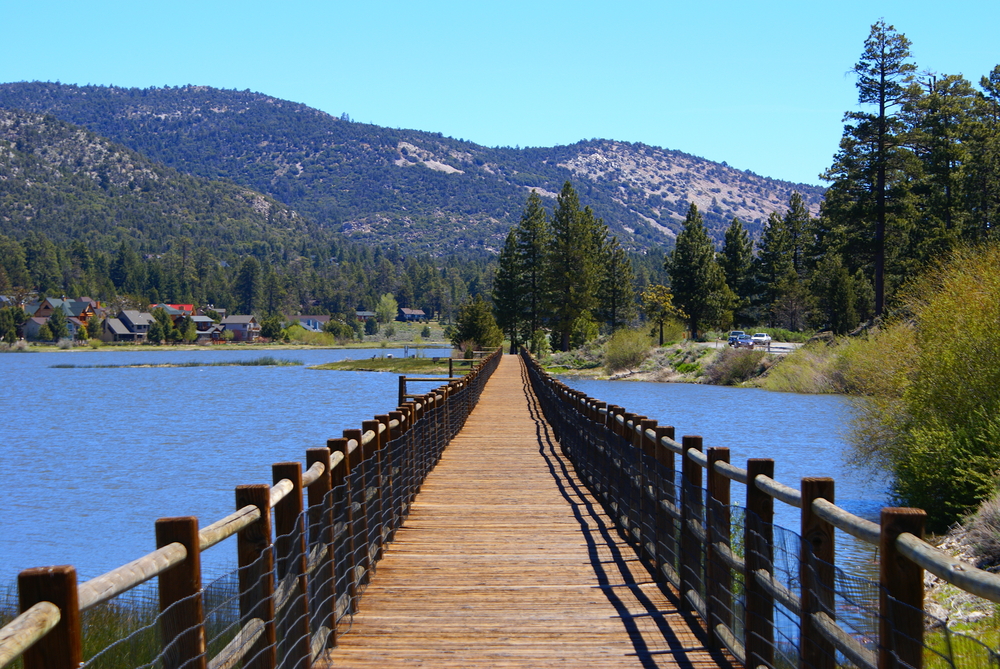 Wooden bridge with metal guards on the side crossing Big Bear during the best time to visit, the Spring