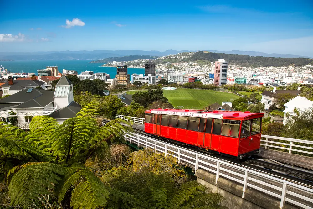Red cable car in Wellington making its way up the mountain with the city and bay below