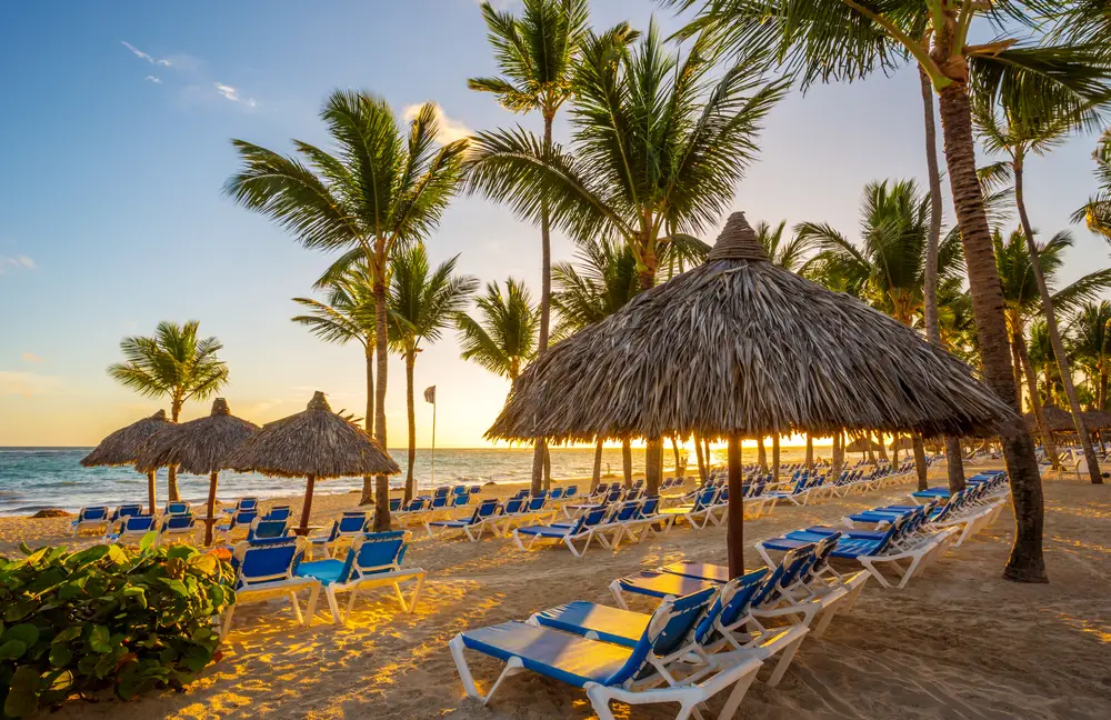 Private resort beach in Punta Cana at sunrise with beach chairs and thatched umbrellas for a safety comparison of Puerto Rico vs the Dominican Republic