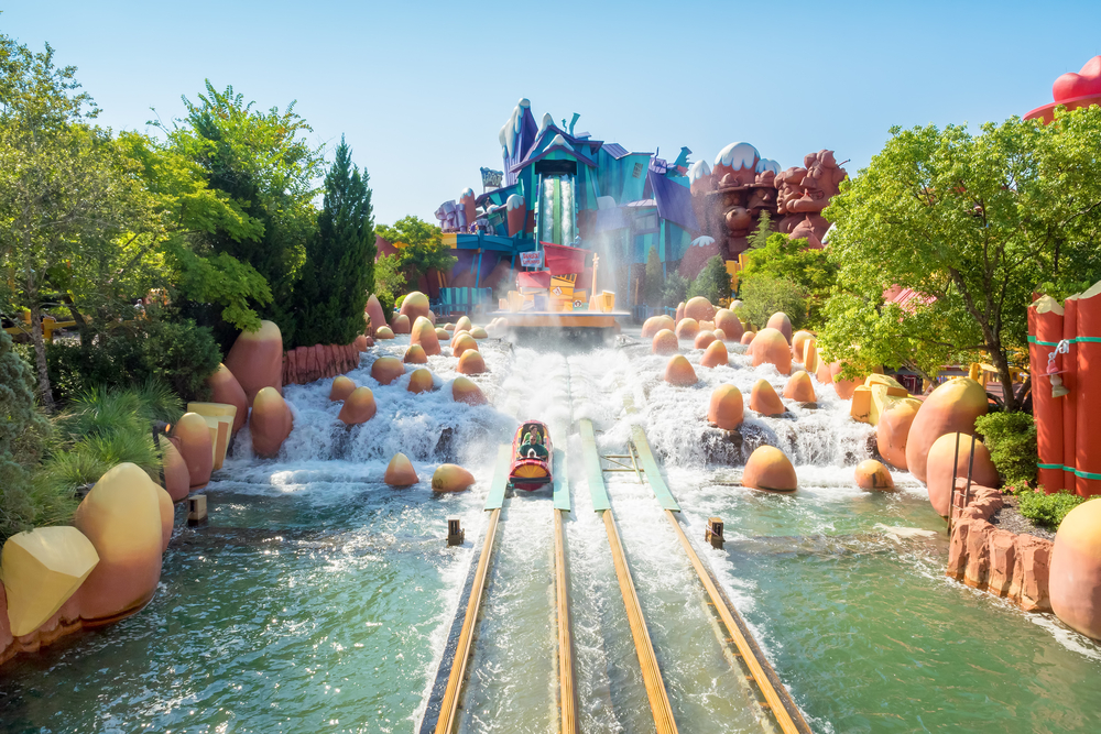 Island of Adventure park pictured with a log ride making a splash into the water