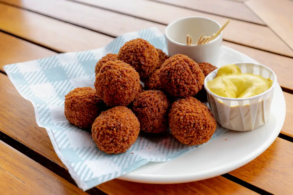 Bitterballen served on a platter with mustard and toothpicks shown as the best Dutch food to try