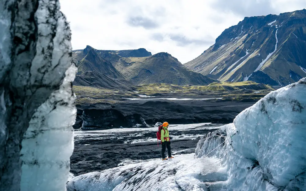 Woman in cold weather gear shown in Iceland, one of the best places for solo travel, standing in Katla Ice Cave in a national park