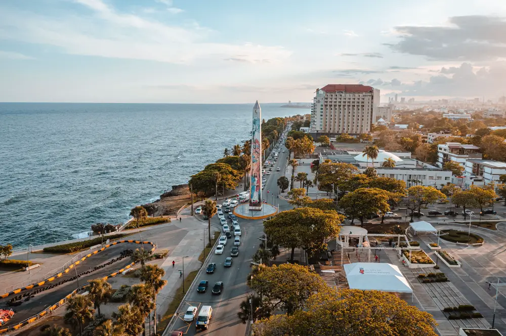 Photo of a sunset over Santo Domingo, one of the best places to stay in the Dominican, pictured with the historic city downtown area next to the ocean
