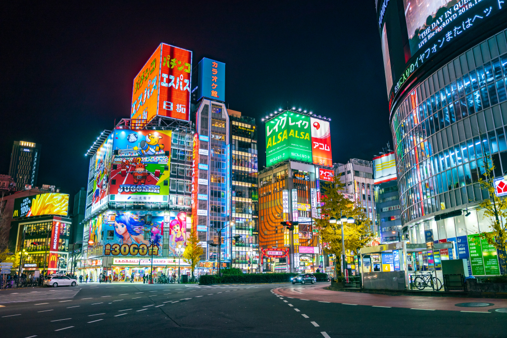 Night cityscape with lots of neon signs pictured with ads on them in one of the best areas to stay in Tokyo, Shinjuku