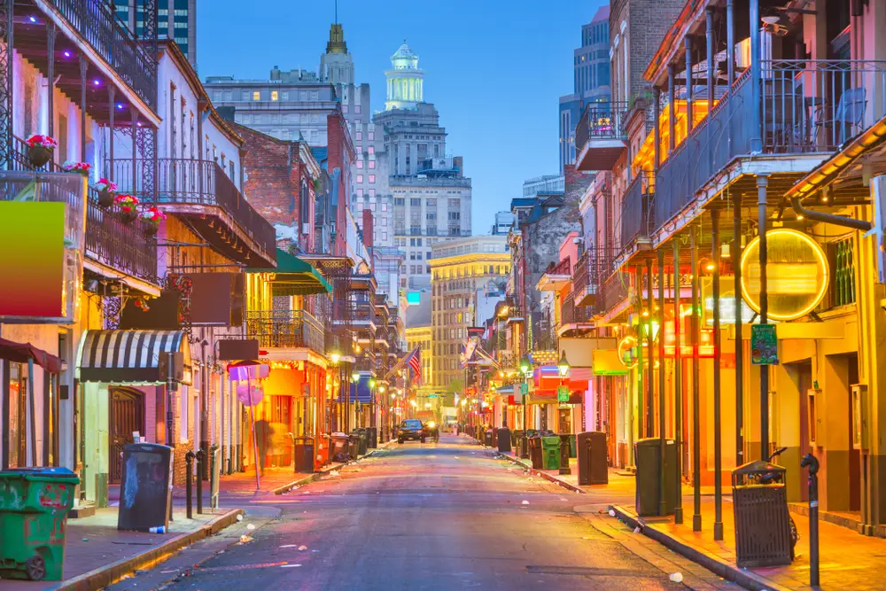 Bourbon Street in New Orleans shown empty with neon lights glowing around the bars and restaurants for a list of the best trips for groups of friends